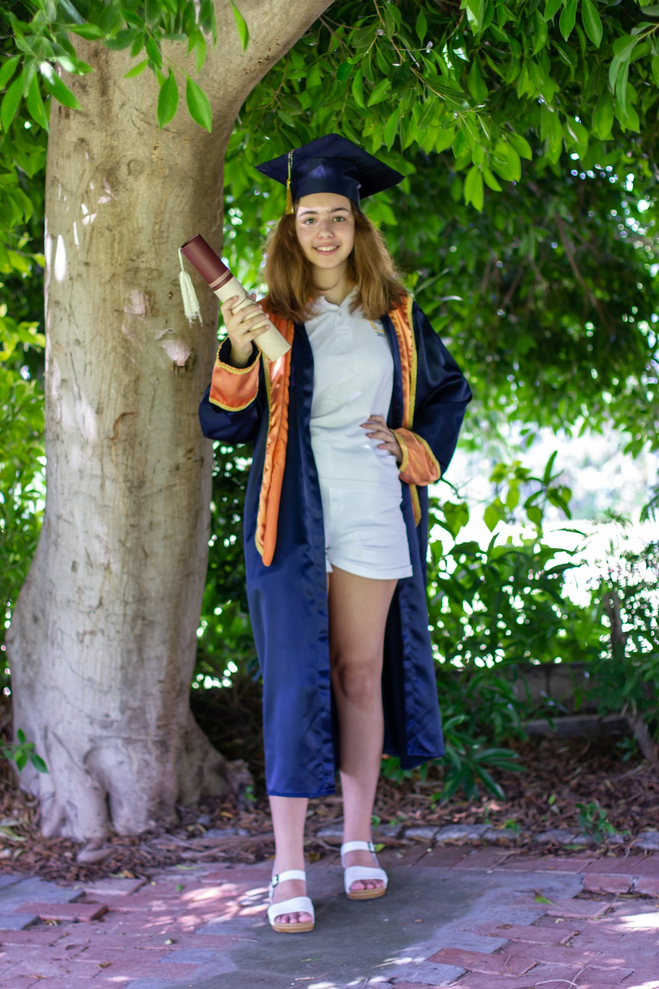 High school graduate. Pretty schoolgirl in graduation cap and mantle.